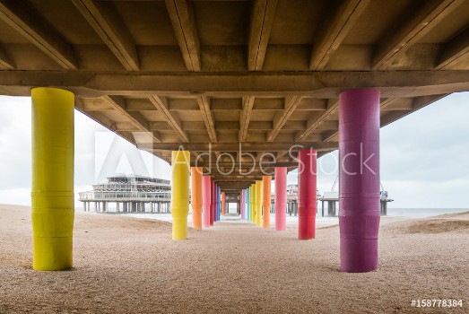 Image de Shot under pier with color painted columns on the beach at sunset